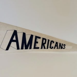 May include: A vintage pennant with a white background and black text. The text reads "New Jersey Americans".