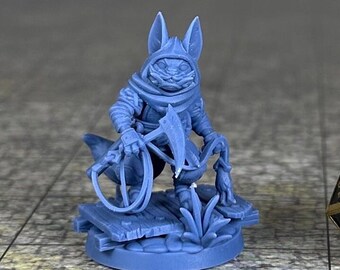 May include: A blue 3D printed miniature of a cat-like creature wearing a hooded cloak and holding a rope with a hook. The miniature is standing on a base with a wooden platform and plants. A black and gold 20-sided die is in the background.