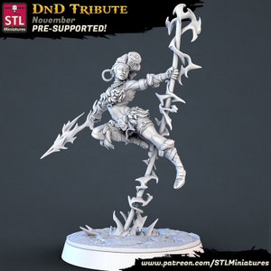 May include: A white 3D printed miniature of a female warrior figure holding a spear. The figure is posed in a dynamic action pose, with one leg raised and the other bent. The figure is wearing a skirt and a bra-like top with a decorative design. The figure is standing on a base with a textured surface. The figure is part of a Dungeons and Dragons Tribute collection.