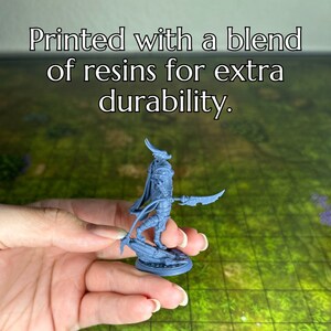 May include: A gray 3D printed miniature of a humanoid figure with horns and a weapon. The figure is standing on a round base. The miniature is printed with a blend of resins for extra durability.
