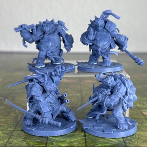 May include: Four blue-gray miniature figurines of turtle-like warriors in various action poses. Two figures hold weapons, while the others stand with weapons. The figures are on square bases, suggesting a tabletop game.