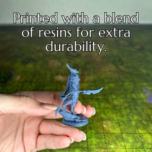 May include: A gray miniature figurine of a creature with horns and a sword, standing on a base. Printed with a blend of resins for extra durability.