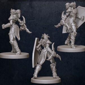 Puede incluir: Tres figuras en miniatura pintadas de gris de una guerrera con un escudo y una daga. Las figuras est&aacute;n en diferentes posturas, mostrando las vistas frontal, posterior y lateral de la figura.