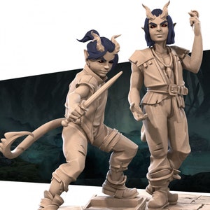 May include: Two painted figurines of a humanoid creature with horns, blue hair, and a tail. One figurine is holding a dagger, the other is holding a small object in their hand.