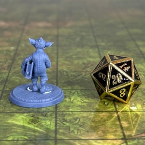 May include: A gray miniature figurine of a goblin wearing a sweater and holding a book. The figurine is standing on a gray base. A black and gold 20-sided die is in the background.