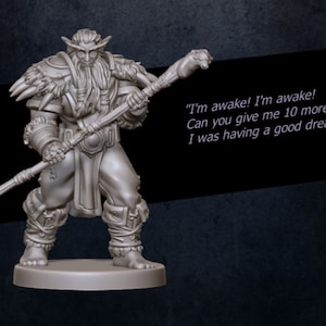 May include: A gray miniature figurine of a bearded, horned, humanoid figure holding a staff. The figure is wearing a fur-lined tunic and leather armor. The text "I'm awake! I'm awake! Can you give me 10 more minutes? I was having a good dream" is written below the figure.