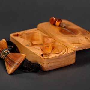 May include: A wooden bow tie with a geometric pattern in green, brown, and white, in a wooden box with a lid.