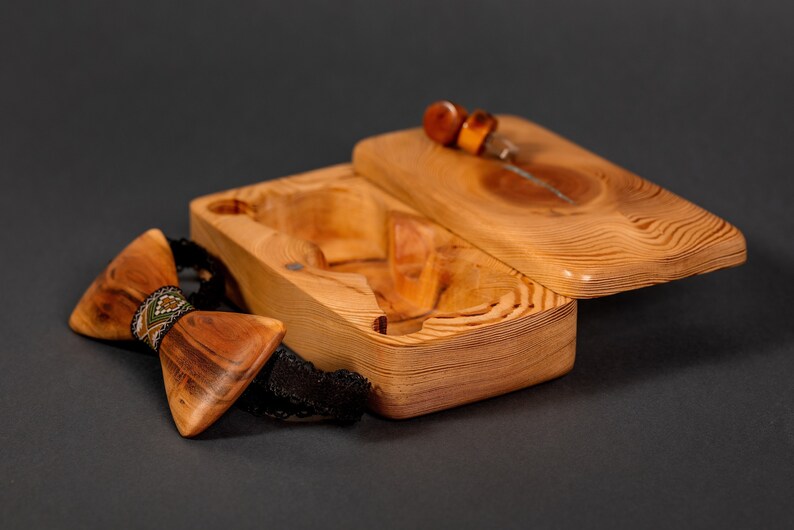 May include: A wooden bow tie with a geometric pattern in green, brown, and white, in a wooden box with a lid.