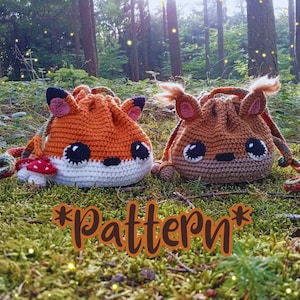 May include: Two crocheted drawstring bags shaped like woodland creatures, a fox and a deer, rest on moss. The fox bag is orange, white, and black, with a mushroom accent. The deer bag is brown with cream accents. The word "pattern" is in the image.