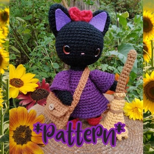 Op de afbeelding: Een handgemaakte zwarte gehaakte kattenpop met een paarse jurk, rode schoenen en een bruine schoudertas. De kat heeft paarse oren en een rode hartvormige strik. Ze houdt een bezem vast en het woord "pattern" staat op de afbeelding.