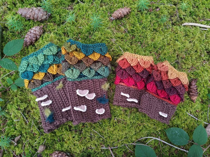 Puede incluir: Guantes sin dedos de ganchillo en tonos marr&oacute;n, verde y rojo, que representan una escena de bosque. Los guantes presentan un dise&ntilde;o texturizado con detalles en forma de hojas y acentos de setas, sobre un fondo de musgo.