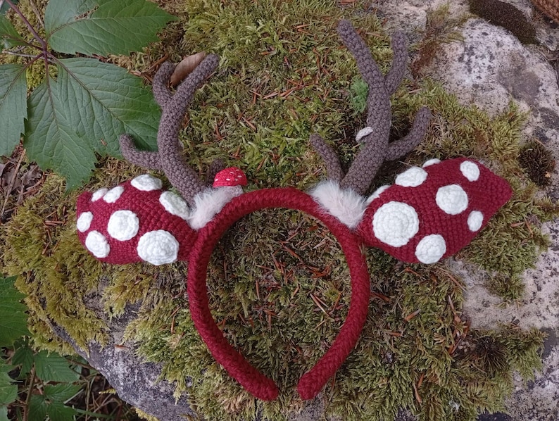 May include: A handmade, red crocheted headband with attached brown antlers and red mushroom-shaped ear covers with white spots. The headband is decorated with white faux fur and a small red mushroom.