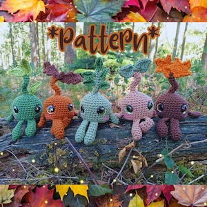 May include: Five crocheted plant creatures with large glossy eyes and leafy tops in green, orange, light green, pink, and brown. The word *Pattern* is written in brown cursive text above the figures, which are arranged on a fallen tree log.