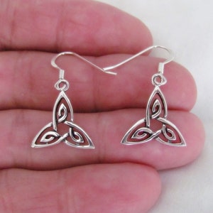 May include: A pair of silver Celtic knot earrings with a triangular design. The earrings are dangle style with a hook closure.