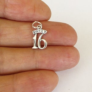 May include: Silver charm with the number 16 and the word "SWEET" above it.