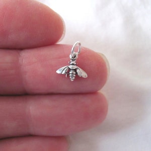 May include: A small silver bee charm with a loop for attaching to a necklace or bracelet.