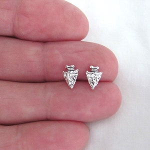 May include: A pair of silver arrowhead stud earrings. The arrowheads are textured and have a rustic look.