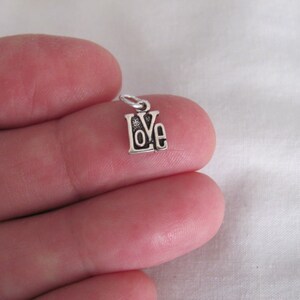 May include: A silver charm with the word "LOVE" in a stylized font.