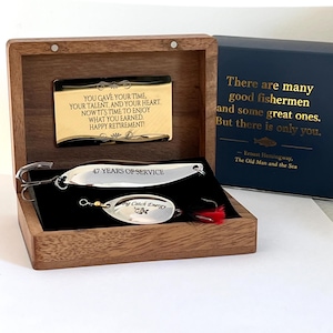 May include: A wooden box containing two silver fishing lures. The top lure is engraved with 47 YEARS OF SERVICE. The bottom lure features the text Big Catch Energy. A gold plaque inside reads YOU GAVE YOUR TIME, YOUR TALENT, AND YOUR HEART.