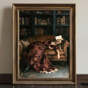Puede incluir: Una pintura enmarcada representa a una persona con un vestido burdeos descansando en un sofá marrón con un libro en la cabeza. Una estantería llena de libros está en el fondo. La pintura está en un marco dorado.