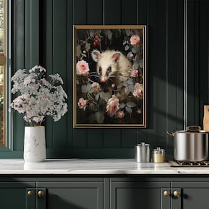 May include: A framed art print featuring a white opossum surrounded by pink roses and greenery. The artwork has a vintage aesthetic with a gold frame, displayed on a dark green wall above a white countertop.