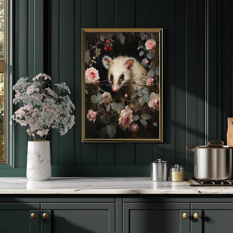 May include: A framed art print featuring a white opossum surrounded by pink roses and greenery. The artwork has a vintage aesthetic with a gold frame, displayed on a dark green wall above a white countertop.
