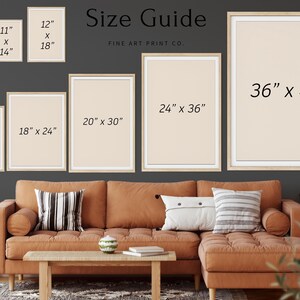 Op de afbeelding: Maattabel voor kunstprints, met verschillende framematen van 9x11 inch tot 36x48 inch. De frames zijn getoond op een muur boven een bruine bank met kussens.
