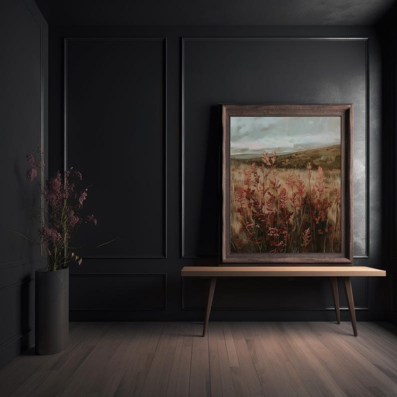 May include: A framed landscape painting featuring a field of red and gold plants under a cloudy sky. The artwork is displayed on a wooden bench in a room with dark walls and a vase of purple flowers.