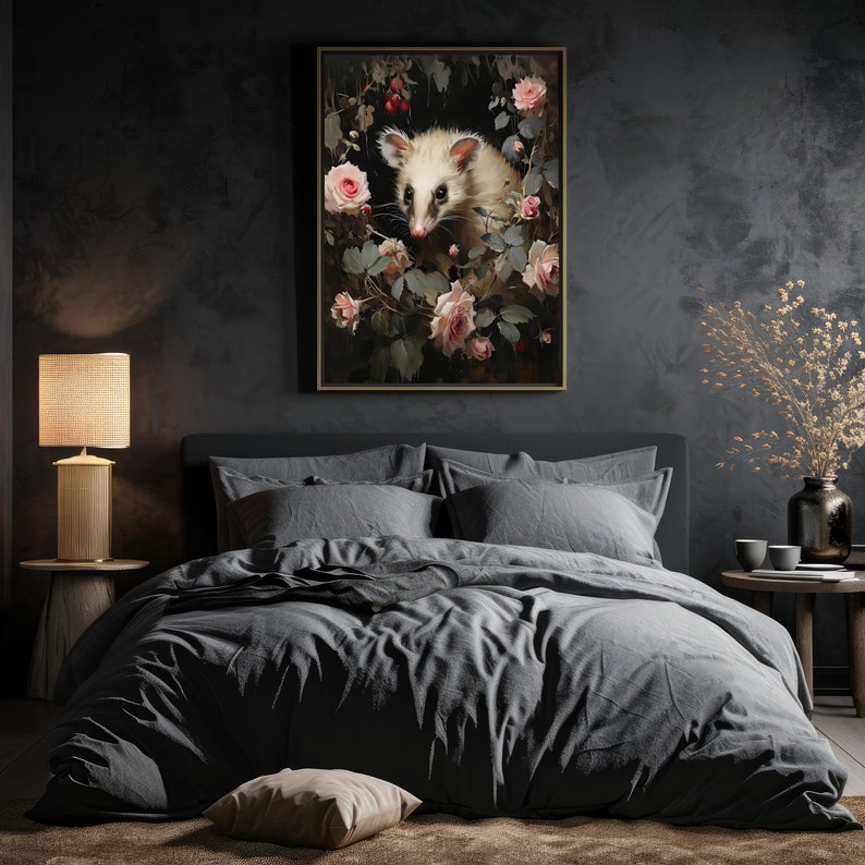 May include: A framed art print featuring a white opossum surrounded by pink roses and greenery. The artwork has a dark, moody aesthetic, with a focus on the opossum's face. The print is displayed above a bed with gray bedding.