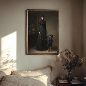 May include: A framed portrait depicts a woman in a long black dress holding a leash attached to a Rottweiler dog. The painting has a gold frame and is set against a neutral wall. A small table and vase are visible in the background.