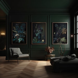 May include: Three framed botanical prints with dark green leaves and flowers in a dark green room with a gray chair and a black couch.