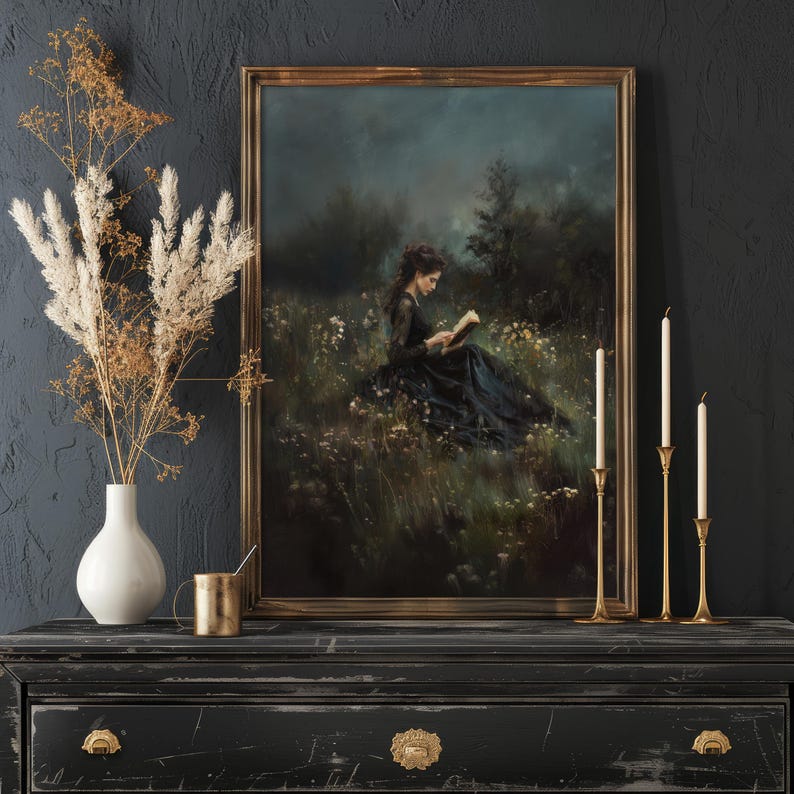 May include: A framed oil painting of a woman in a black dress sitting in a field of wildflowers, reading a book. The painting has a dark, moody atmosphere and is set against a dark gray background.