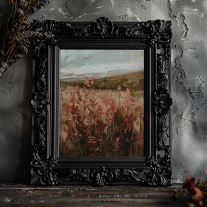 May include: A framed landscape painting featuring a field of tall, reddish-brown plants under a cloudy sky. The artwork is enclosed in a black, ornate frame with detailed carvings. The painting evokes a sense of nature and tranquility.
