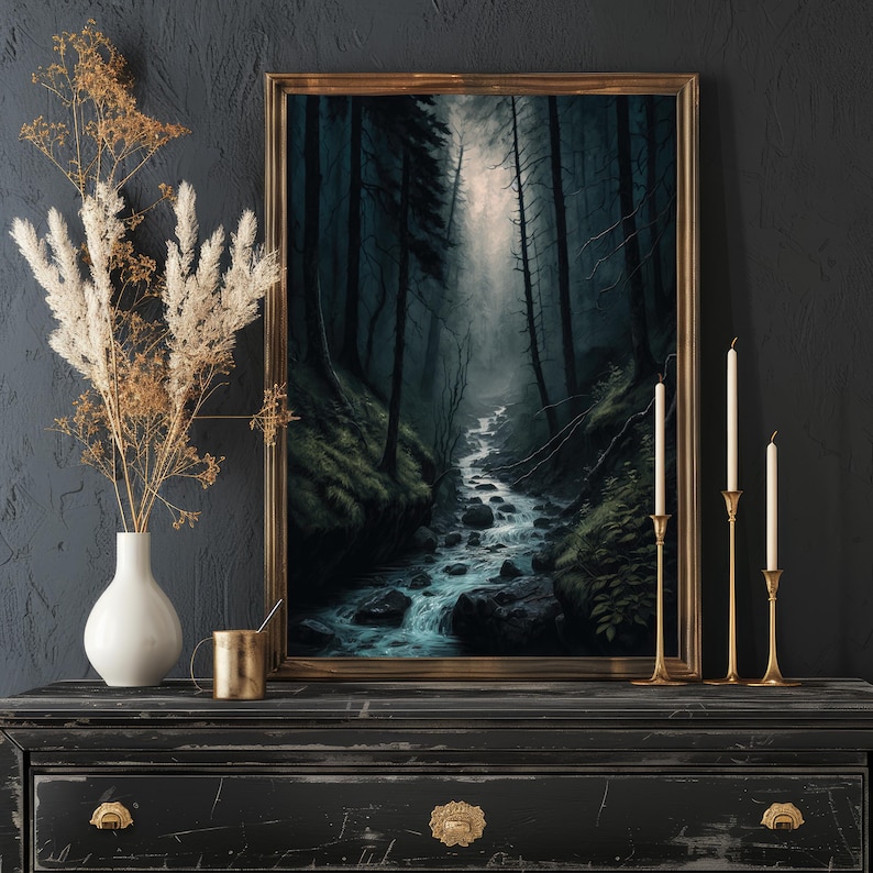 Op de afbeelding: Een ingelijst schilderij van een donker bos met een beek die erdoorheen stroomt. De beek is omgeven door bomen en rotsen, en het licht komt van boven. Het schilderij is in een gouden lijst en hangt aan een zwarte muur.
