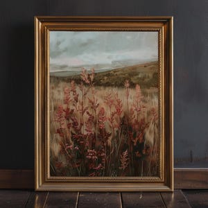 May include: A framed landscape painting featuring a field of tall, reddish-pink grasses in the foreground. The background shows rolling hills under a cloudy sky. The painting is in a gold-colored frame.