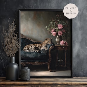 May include: A framed art print depicting a leopard reclining on a dark blue chaise longue. A vase of pink roses sits on a small table. The artwork has a vintage aesthetic with a dark, moody colour palette.