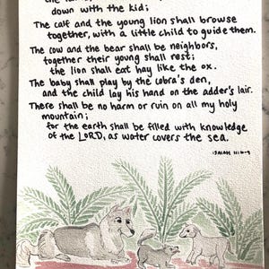 May include: Watercolor illustration of a wolf, lamb, and a young lion with a quote from Isaiah 11:6-9: "Then the wolf shall be a guest of the lamb, and the leopard shall lie down with the kid; The calf and the young lion shall browse together, with a little child to guide them. The cow and the bear shall be neighbors, together their young shall rest; the lion shall eat hay like the ox. The baby shall play by the cobra's den, and the child lay his hand on the adder's lair. There shall be no harm or ruin on all my holy mountain; for the earth shall be filled with knowledge of the LORD, as water covers the sea."