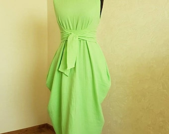 May include: A lime green sleeveless dress with a wrap-style bodice and a bow at the waist. The dress is made of a lightweight, textured fabric and has a flowing silhouette.