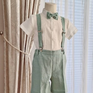 May include: A white linen shirt with a green bow tie and matching green linen shorts with suspenders.