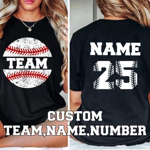 May include: Black t-shirt with a white baseball graphic and the word "TEAM" on the front. The back of the shirt has a white baseball graphic with the text "NAME" and the number "25".