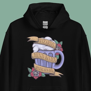 May include: Black hoodie with a graphic of a purple beer mug with white foam and a yellow banner that says "Wizards Mind Bomb Rising Sun Inn".