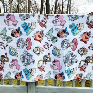 Może przedstawiać: Biała tkanina z powtarzającym się wzorem postaci z Toy Story. Postacie to Woody, Buzz Astral, Jessie, Pan i Pani Potato Head, Rex i Slinky Dog.