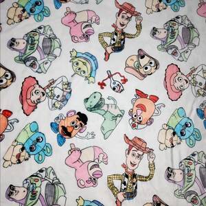 Może przedstawiać: Biała tkanina z powtarzającym się wzorem postaci z Toy Story. Postacie to Woody, Buzz Astral, Pan Potato Head, Jessie i Obcy. Postacie są narysowane w kresk&oacute;wkowym stylu i są kolorowe.