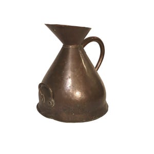 May include: A copper-coloured jug with a conical body and a flared spout. It features a curved handle and a small, decorative handle on the side. The jug is made of metal and has a vintage appearance.