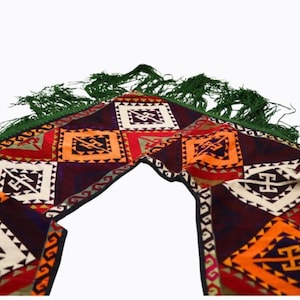 May include: A colorful rug with a geometric pattern and green fringe. The rug is made of a soft, woven fabric and has a traditional design.