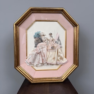 Può includere: Un'opera d'arte da parete incorniciata di forma ottagonale che presenta una scena in découpage tridimensionale di due figure in abiti d'epoca. La cornice è dorata con un bordo interno rosa. Le figure indossano abiti in tessuto rosa, crema e bianco.