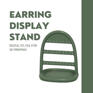 Puede incluir: Un expositor de pendientes de plástico verde con tres niveles de agujeros para pendientes. El expositor tiene una base redondeada y una parte superior curva. DIGITAL STL FILE FOR 3D PRINTING está escrito debajo del expositor.