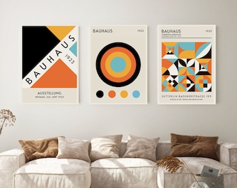 May include: Three Bauhaus art prints with geometric designs in black, white, orange, yellow, and blue. The prints feature the Bauhaus logo and the year 1923. The text on the prints reads "Bauhaus", "Ausstellung Weimar, Juli, Sept 1923", and "Sutterlin Badenerstrasse 109 School of Art Design and Architecture".