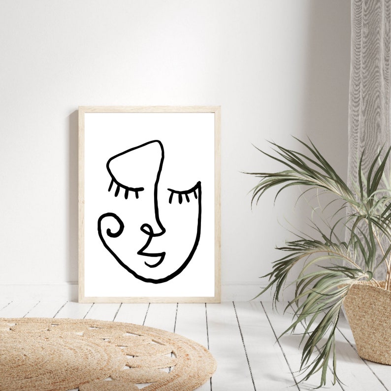 Pu&ograve; includere: Un disegno in bianco e nero di un viso con gli occhi chiusi, un naso e una bocca. Il disegno &egrave; su sfondo bianco ed &egrave; incorniciato in una cornice di legno chiaro.