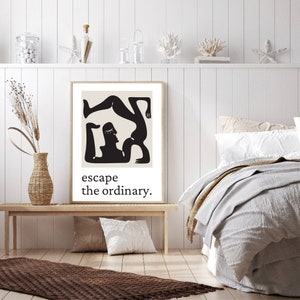 May include: Black and white illustration of two figures in a yoga pose. The image is framed and has the text "escape the ordinary." below the illustration.